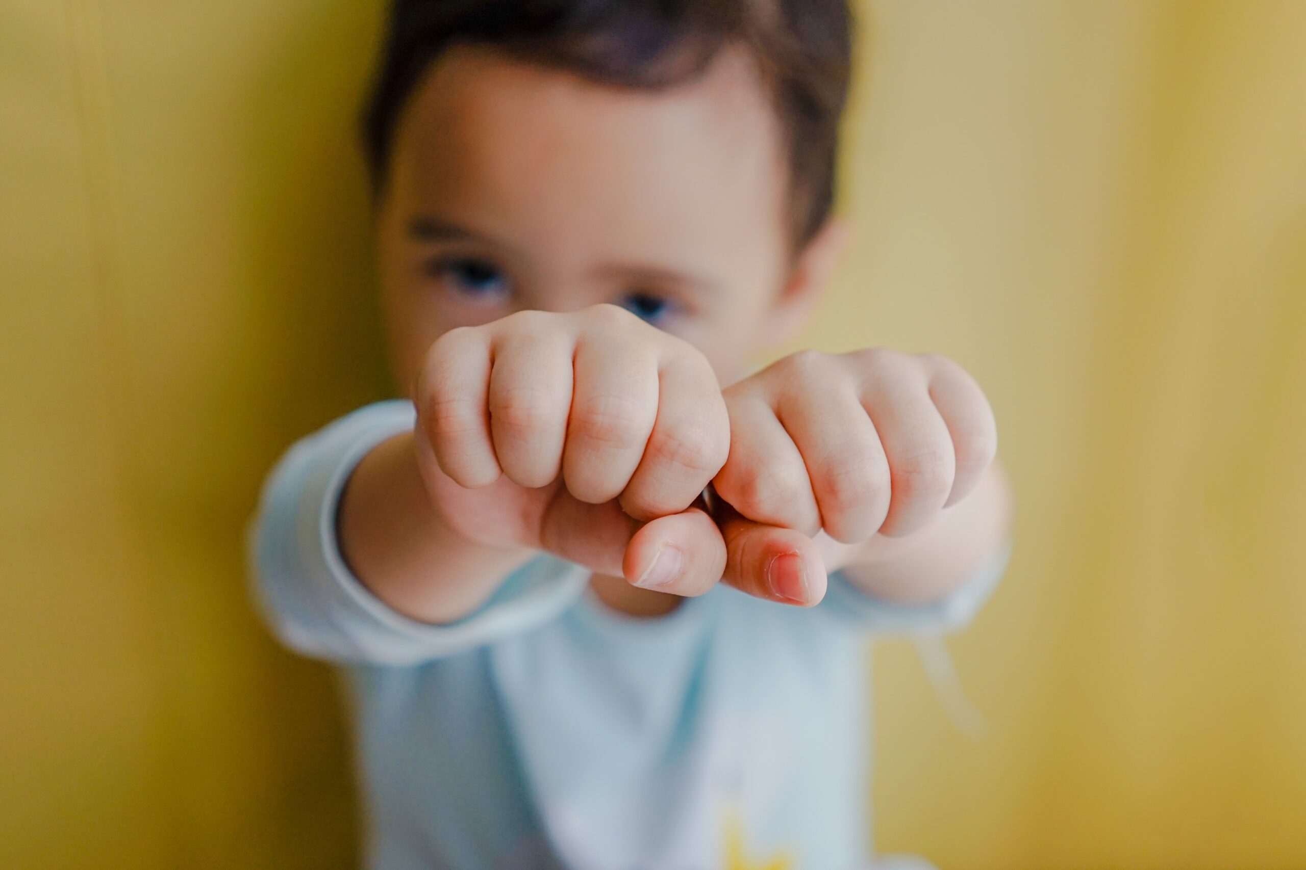 Un petit garçon montre ses poings fermés - langue des signes en maternelle